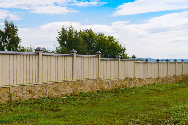 Wooden fence painted yellow with a stone base